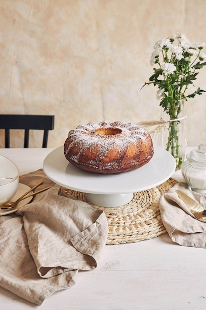 Bela foto de um bolo delicioso colocado em um prato branco e uma flor branca perto dele