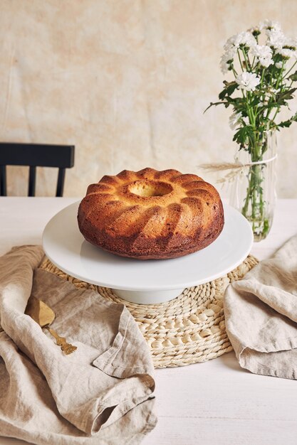 Bela foto de um bolo delicioso colocado em um prato branco e uma flor branca perto dele