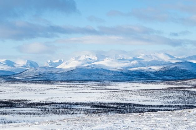 Bela foto de um campo nevado e montanhas ao longe, no norte da Suécia