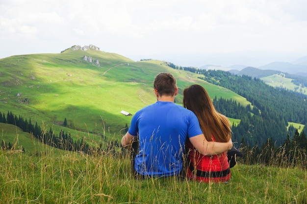 Bela foto de um casal sentado em um campo de montanha