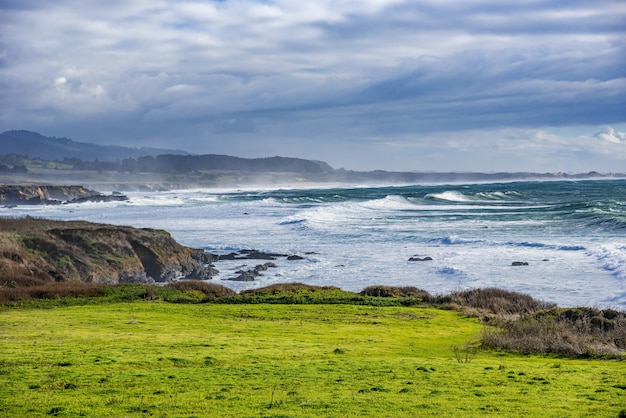 Foto grátis bela foto de um farol em uma formação rochosa verde na costa do oceano