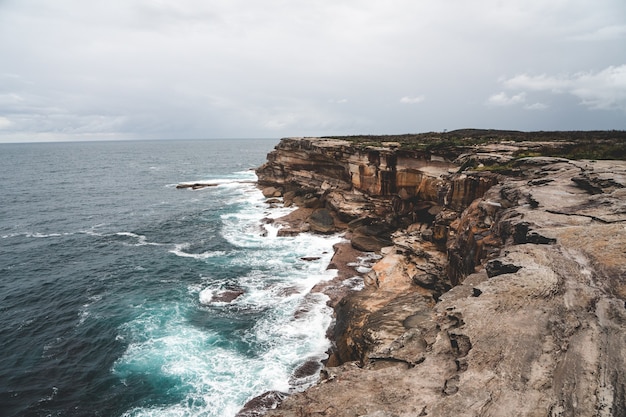 Bela foto de um grande penhasco próximo à água azul em um dia sombrio