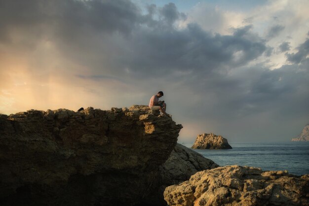 Bela foto de um homem sentado à beira-mar