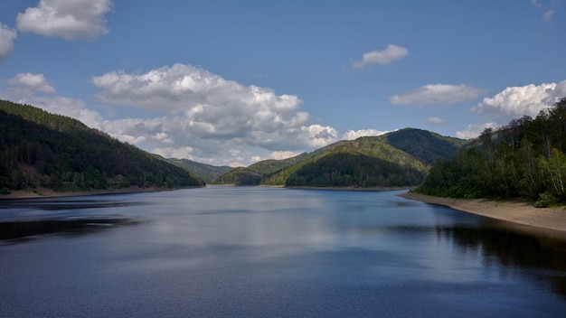 Bela foto de um lago cercado por montanhas com o reflexo do céu na água