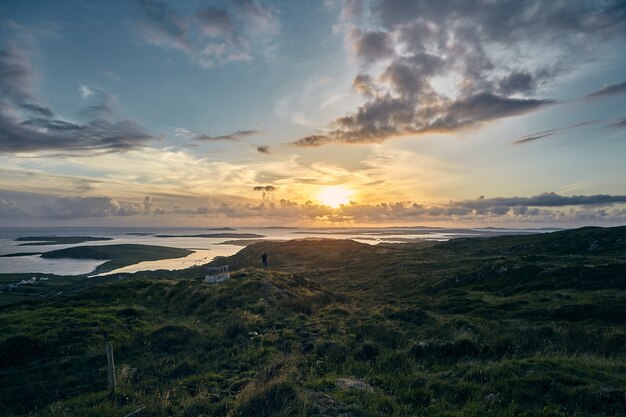 Bela foto de um pôr do sol na Sky Road, Clifden, na Irlanda, com campos verdes e oceano