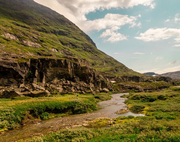 Bela foto de um rio que flui perto de altas montanhas rochosas na Noruega