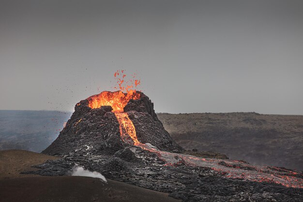 Bela foto de um vulcão ativo com lava fluindo e fumaça sob um céu claro