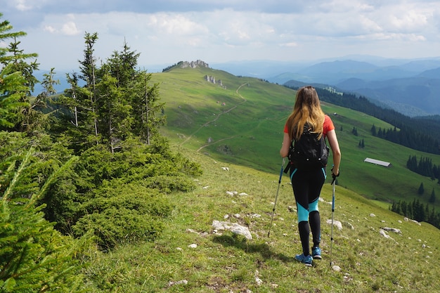 Bela foto de uma alpinista caminhando na montanha sob o céu azul no verão