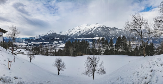 Bela foto de uma cadeia de montanhas cercada por pinheiros em um dia de neve