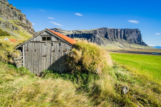 Bela foto de uma casa de madeira em um campo na Islândia