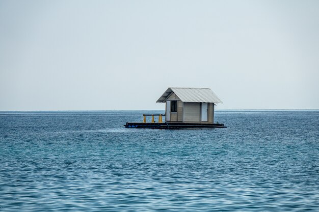 Bela foto de uma casa flutuante em um oceano azul com um céu claro e branco no