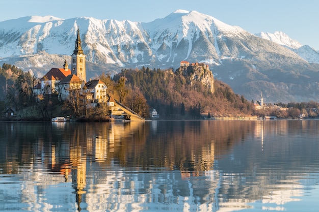 Bela foto de uma casa perto do lago com o monte Ojstrica em Bled, Eslovênia