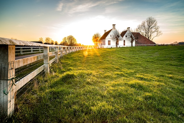 Bela foto de uma cerca que leva a uma casa em uma área de grama verde