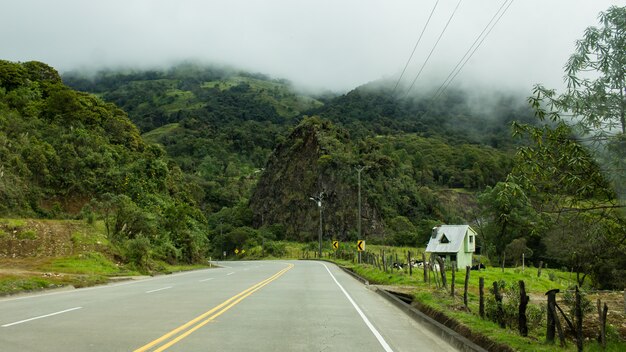 Bela foto de uma estrada curva vazia no campo com nuvens surpreendentes durante um dia enevoado