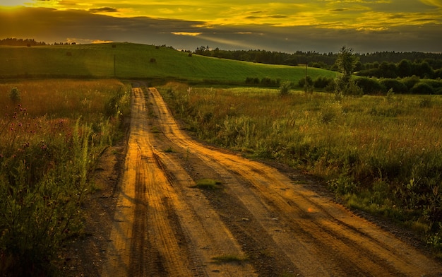 Bela foto de uma estrada no campo durante o pôr do sol deslumbrante