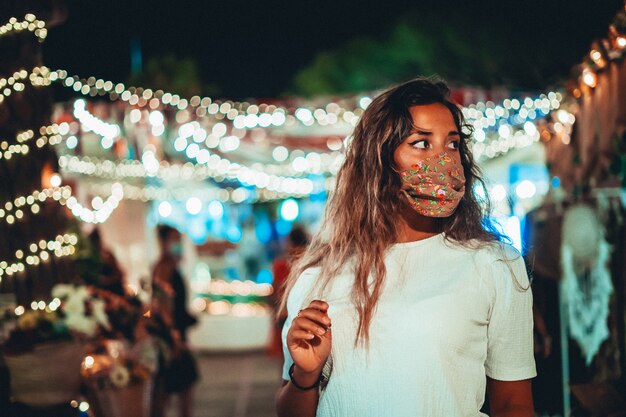 Bela foto de uma europeia bronzeada usando uma máscara floral em um parque de diversões