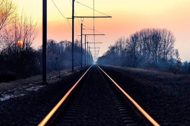 Bela foto de uma ferrovia no campo com o incrível céu rosa ao amanhecer