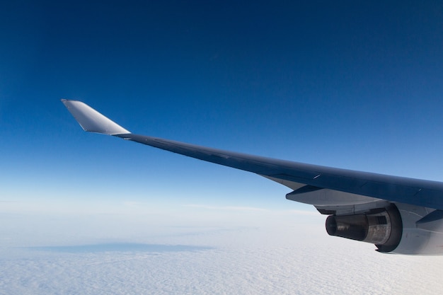 Bela foto de uma janela de avião das asas sobre as nuvens