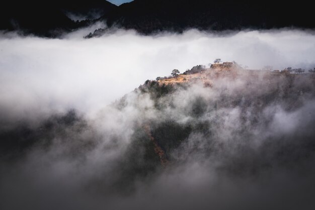 Bela foto de uma montanha acima do nevoeiro