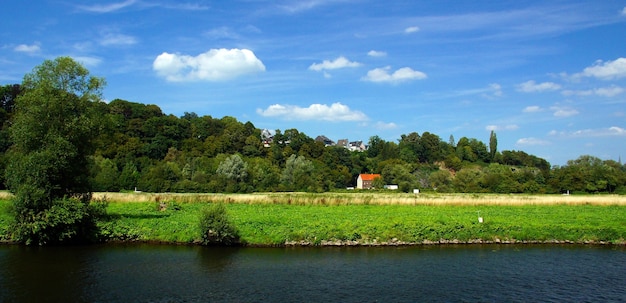 Bela foto de uma pequena casa ao redor de árvores verdes e um campo gramado em um dia nublado