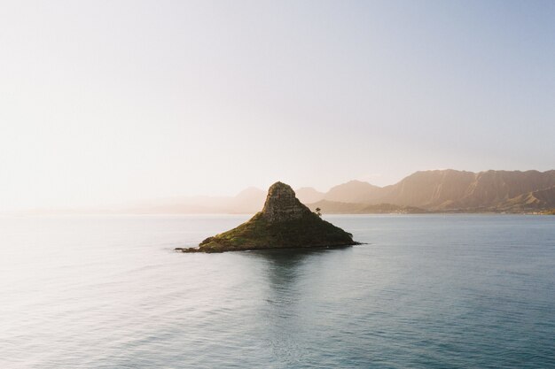 Bela foto de uma pequena ilha no centro do mar aberto com um cenário do nascer do sol