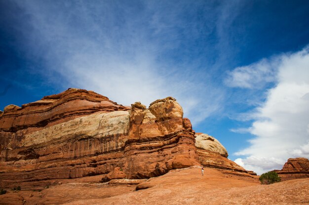 Bela foto de uma pessoa correndo em direção ao penhasco deserto sob um céu nublado