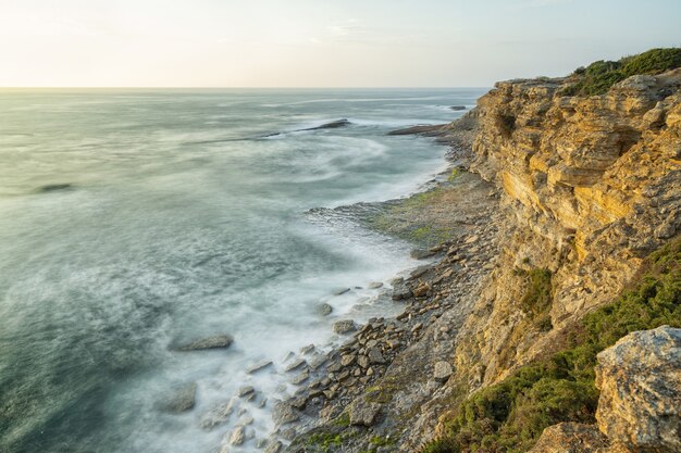 Bela foto de uma praia com um cenário do pôr do sol em um céu claro