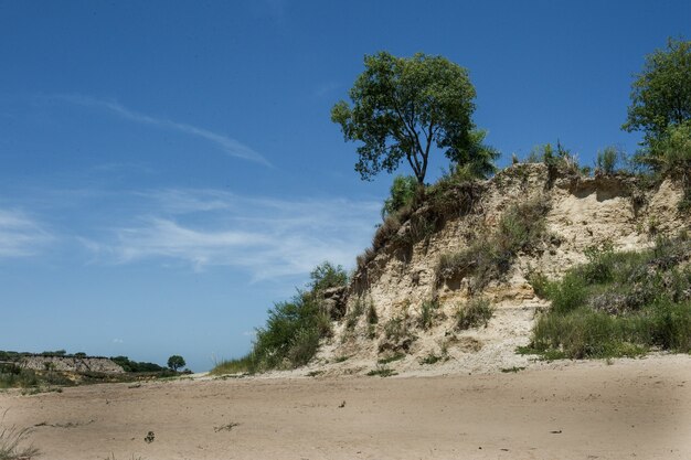 Bela foto de uma praia vazia com um penhasco sob um céu azul