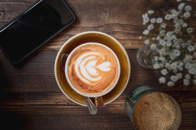 Bela foto de uma xícara de cappuccino com um padrão de coração branco em uma mesa de madeira