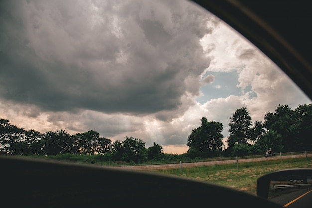 Foto grátis bela foto do céu nublado acima de árvores tiradas de um carro