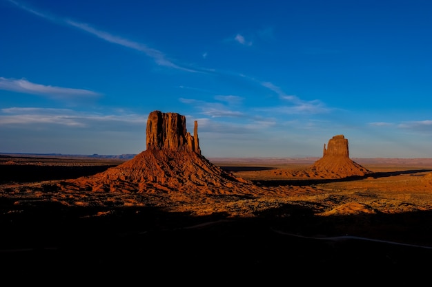 Bela foto do deserto com arbustos secos e grandes falésias à distância sob um céu azul