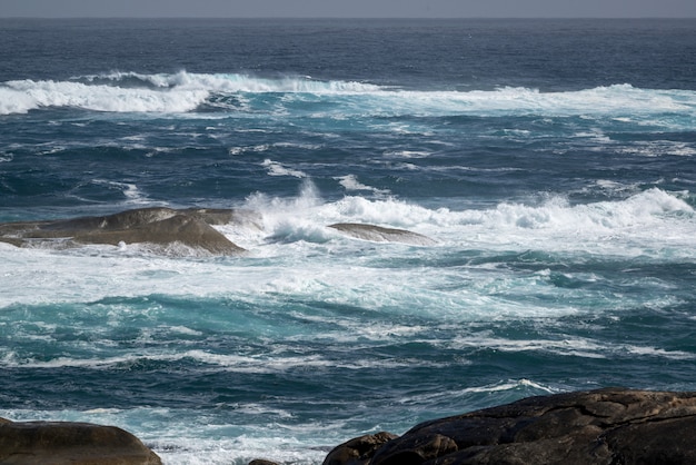 Bela foto do oceano ondulado com algumas pedras na água