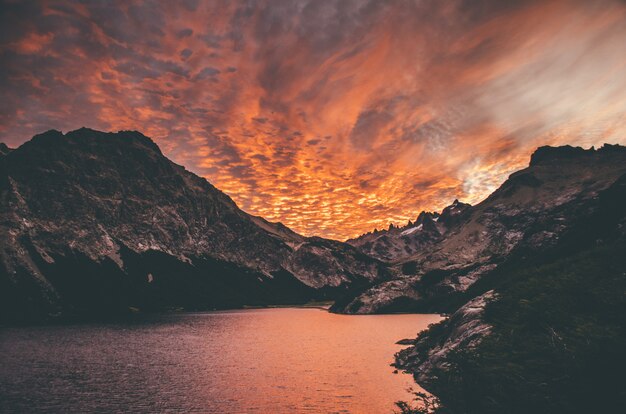 Bela foto do pôr do sol nas montanhas à beira do lago com nuvens incríveis