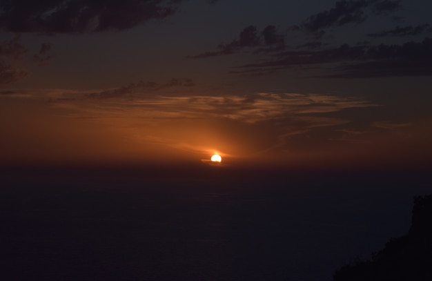 Bela foto do pôr do sol nublado sobre as falésias e o mar em Malta