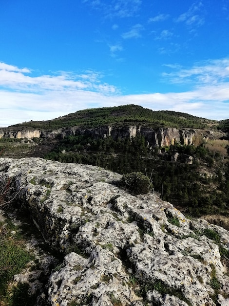 Bela foto vertical de montanhas e vegetação sob um céu azul em Cuenca, Espanha