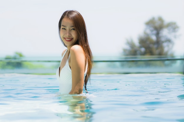 Bela jovem asiática feliz e sorrir na piscina para relaxar, viajar e férias