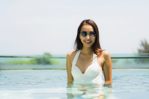 Bela jovem asiática feliz e sorrir na piscina para relaxar, viajar e férias