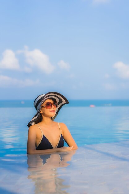 bela jovem asiática relaxar ao redor da piscina no resort hotel