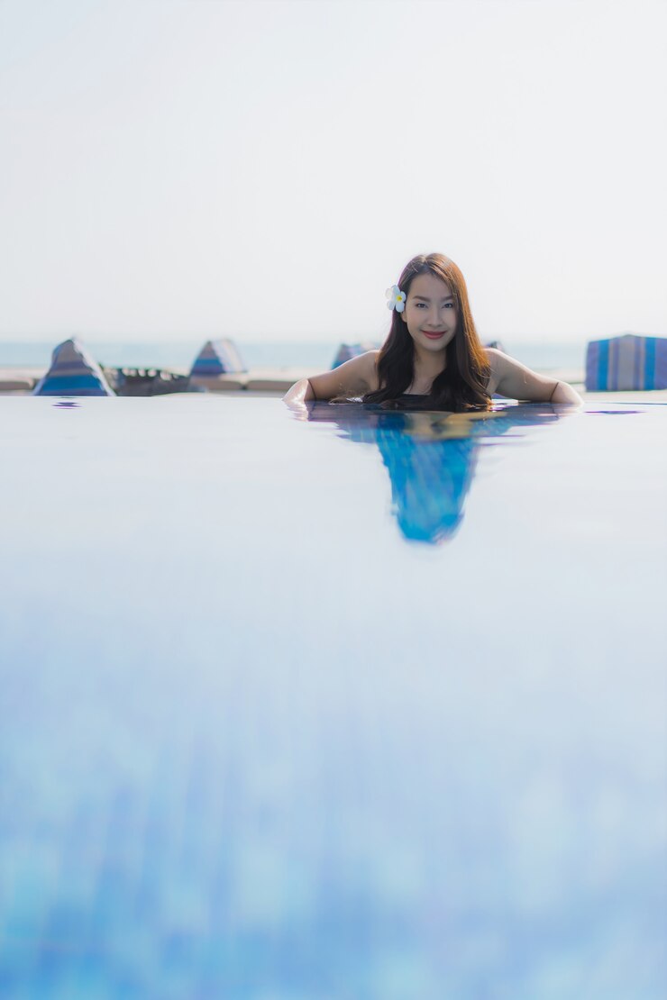 Foto grátis bela jovem asiática sorrindo feliz e relaxando na piscina.