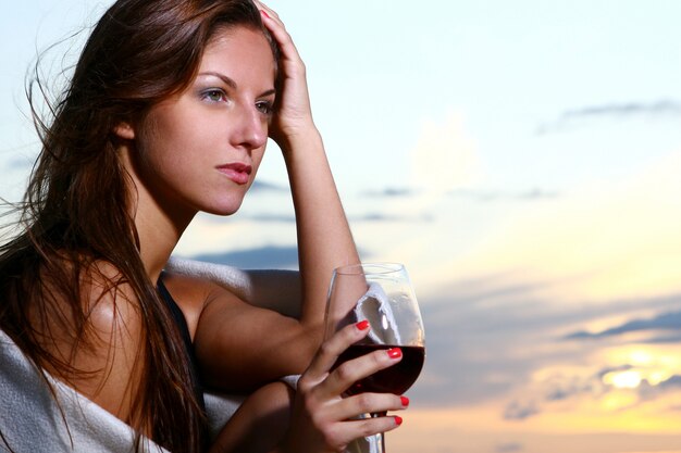 Bela jovem bebendo vinho na praia