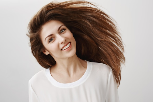 Bela jovem chicote de cabelo e sorrindo. Conceito de cuidados com os cabelos