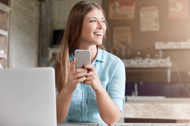 Bela jovem com cabelo comprido sentada num café com um laptop