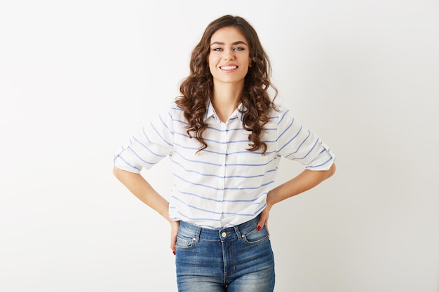 Bela jovem com sorriso sincero, estilo hippie, vestida com jeans, camisa, isolada no fundo branco, cabelos cacheados