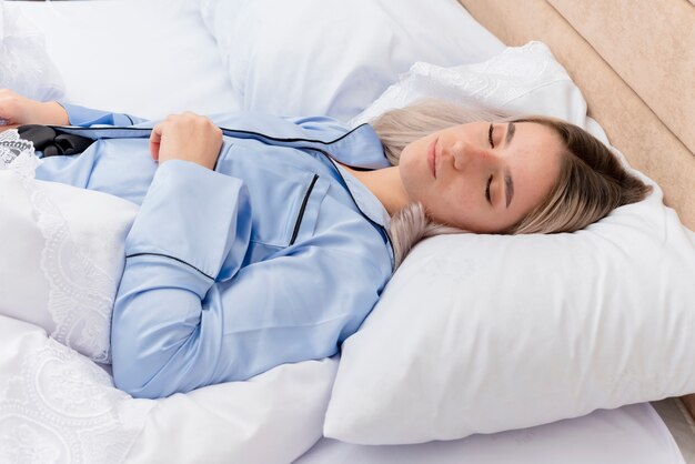 Bela jovem de pijama azul deitada na cama