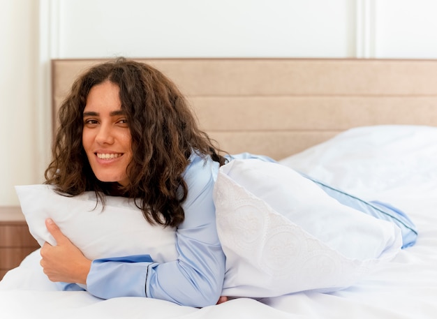 Bela jovem de pijama azul deitada na cama