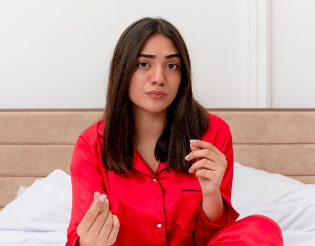 Bela jovem de pijama vermelho relaxando na cama