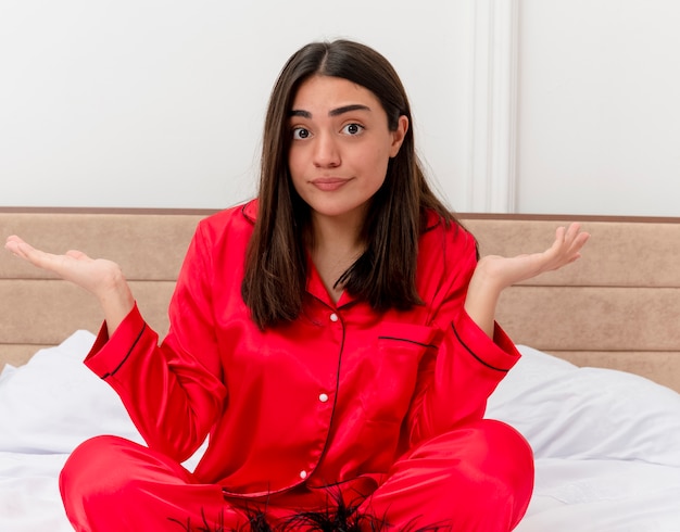 Bela jovem de pijama vermelho relaxando na cama