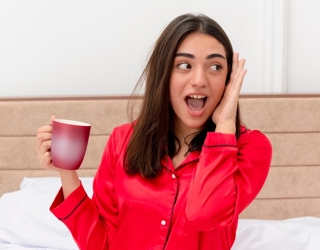 Bela jovem de pijama vermelho relaxando na cama