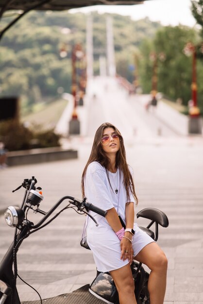 Bela jovem e uma scooter elétrica de transporte ecológico