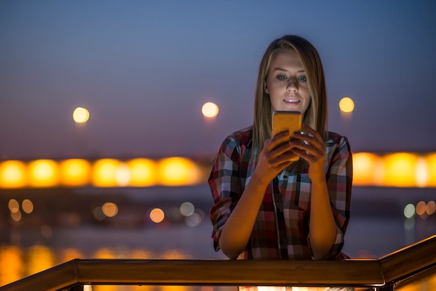 Bela jovem falando no celular na cidade noturna.